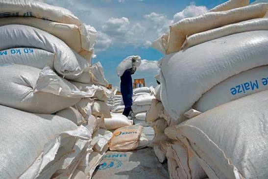 Assorted food aid supplies – RUTF sachets, fortified flours, vegetable oil, and Super Cereal arranged on a pallet for humanitarian distribution in Uganda.