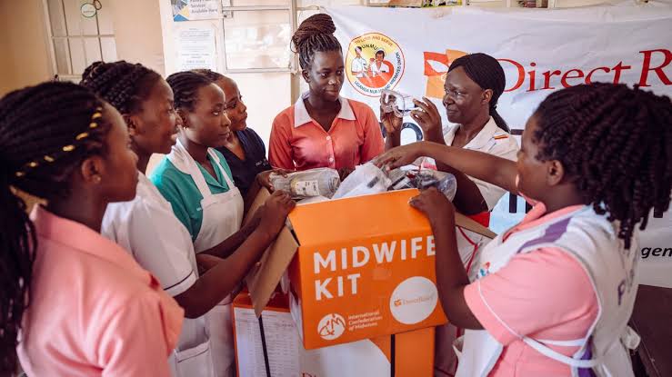 Assorted humanitarian equipment kits – emergency shelter tents, WASH hygiene packs, medical trauma boxes, and solar-powered field communication gear arranged on a pallet, ready for distribution in Uganda.